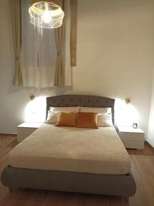 een slaapkamer met een bed met 2 tafels en een kroonluchter bij Appartamento Aretusa di G&G in Siracusa