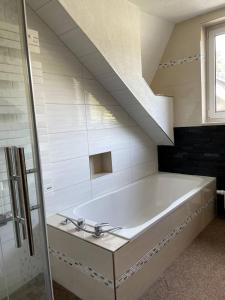 Schleusingen的住宿－Urlaub-Im-Erletal，一间带楼梯的浴室内的白色大浴缸