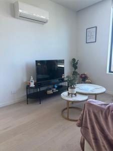 a living room with a tv and a table at Top Floor Mountain View Luxury Rental Unit in SkyGarden Glen in Glen Waverley