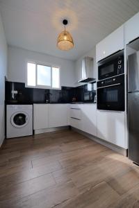 a kitchen with white cabinets and a washer and dryer at Résidence Terre et Passion in Ducos