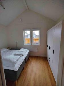 a small bedroom with a bed and two windows at Strandbyn - Destination Råbocka in Ängelholm