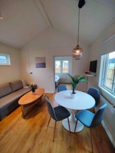 ein Wohnzimmer mit einem Tisch, Stühlen und einem Sofa in der Unterkunft Strandbyn - Destination Råbocka in Ängelholm
