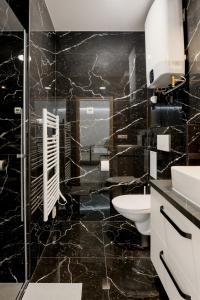 La salle de bains en marbre noir est pourvue d'un lavabo et de toilettes. dans l'établissement BALANCE apartments, à Znojmo