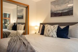 a bedroom with a bed with blue and white pillows at Steps From The Village with Pool and Hot Tub by Harmony Whistler in Whistler +15 photos