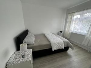 a bedroom with a bed with a table and a window at Warwick Avenue Residency in Northolt