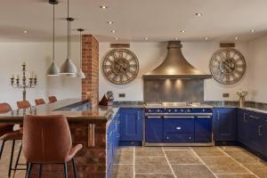 une grande cuisine avec des placards bleus et une cuisinière dans l'établissement A true British country escape!, à Bucknell