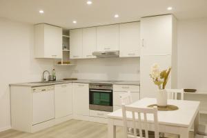a kitchen with white cabinets and a table with a vase of flowers at Ferienwohnung Endingen am Kaiserstuhl in Endingen