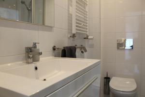 een witte badkamer met een wastafel en een toilet bij Duinzicht 2 in Bergen aan Zee