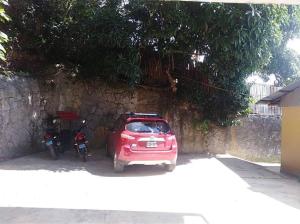 une petite voiture et une moto garées à côté d'un mur dans l'établissement Alojamiento Los Jardines, à Lamas