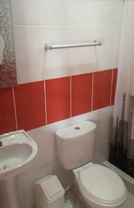 La salle de bains est pourvue de toilettes blanches et d'un lavabo. dans l'établissement Alojamiento Los Jardines, à Lamas