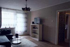 a living room with a couch and a tv at Vieno kambario butas Gedimino g. in Tauragė