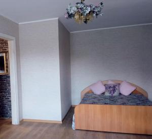 a bedroom with a bed with pink pillows and a chandelier at Vieno kambario butas Gedimino g. in Tauragė