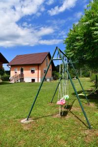 a swing set in a yard with a house at Holiday Home Vukovic in Saborsko