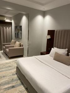 Un dormitorio con una gran cama blanca y un sofá. en شقق البندقية للوحدات الفندقية ALBUNDUQI HOTEl, en Riad