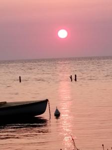 um barco sentado na água com um pôr do sol em APPARTAMENTO Exclusive em Marsala