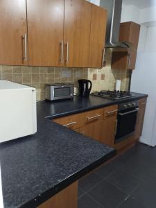 uma cozinha com armários de madeira e um balcão preto em Affordable rooms in Gillingham em Gillingham
