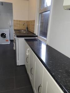 uma cozinha com um balcão preto e um lavatório em Affordable rooms in Gillingham em Gillingham