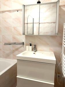 Un baño con lavabo, espejo y bañera. en Center Apartment with 360° Rooftop, en Viena