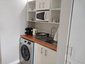 a kitchen with a washing machine and a microwave at Ships Bell 17B in St Francis Bay