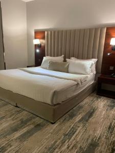 1 dormitorio con 1 cama grande con sábanas y almohadas blancas en شقق البندقية للوحدات الفندقية ALBUNDUQI HOTEl, en Riad