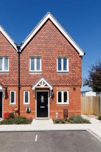 a red brick house with a black door at Sanderling House, walk to beach in Earnley