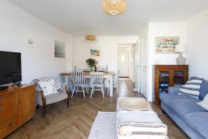 a living room with a blue couch and a table at Sanderling House, walk to beach in Earnley