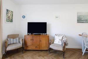 a living room with two chairs and a flat screen tv at Sanderling House, walk to beach in Earnley