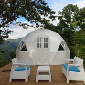 uma tenda cúpula branca com 2 cadeiras e uma mesa em Glamping Rio Melcocho em Cocorná