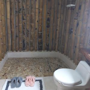 baño con aseo y 2 zapatos en el suelo en Glamping Rio Melcocho en Cocorná