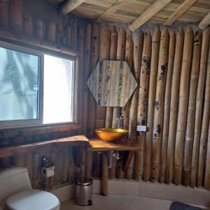 bagno con parete in legno, finestra e ciotola di Glamping Rio Melcocho a Cocorná