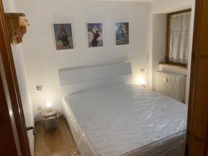 un lit blanc dans une chambre éclairée par deux lumières dans l'établissement PI.GI.'s apartment, à Pré-Saint-Didier