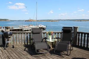 a deck with three chairs and a table and a boat at Cabin at the sea. public beach close with jumpingtower. in Höviksnäs
