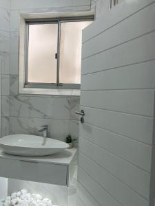 a white bathroom with a sink and a window at Amanzimtoti Afsaal Holiday Letting in Amanzimtoti