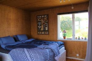 um quarto com uma cama com lençóis azuis e uma janela em Cabin at the sea. public beach close with jumpingtower. em Höviksnäs