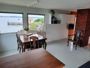 uma sala de jantar com mesa e cadeiras e uma grande janela em Cabin at the sea. public beach close with jumpingtower. em Höviksnäs