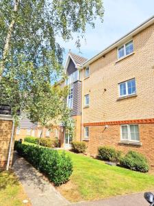 a large brick building with a grass yard at Spacious Luxury Serviced Apartment Stevenage Free Private Parking & WIFI by Stay Local Home Welcome Contractors Business Travellers Families in Stevenage