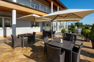 un patio con tavoli, sedie e ombrelloni di Hotel Atena Wedding, Business & Spa a Ciechanów