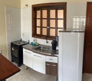 a kitchen with a refrigerator and a sink and a stove at Recanto da Gabi in Ubatuba