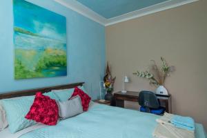 a bedroom with a bed with red pillows and a desk at Kurranulla Sapphire - U2 in Cronulla