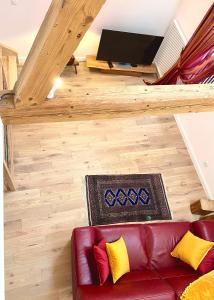 uma sala de estar com um sofá de couro vermelho e uma televisão de ecrã plano em Le Gîte de la Grange em La Wantzenau