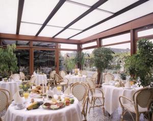 un comedor con mesas y sillas blancas y ventanas en Hotel Hasselbarth, en Burg auf Fehmarn