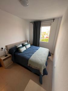 een slaapkamer met een blauw bed en een raam bij Apartamento LOLO in El Médano
