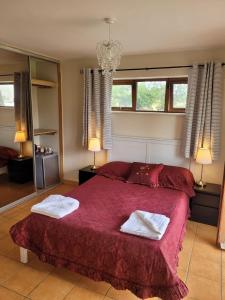 a bedroom with a red bed with two towels on it at Brigadoon lakeview room in Roundwood