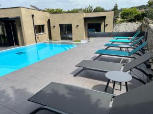a row of lounge chairs and a swimming pool at La Villa Cosy in Espalion