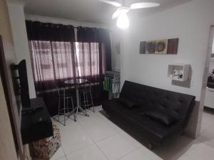 ein Wohnzimmer mit einem schwarzen Sofa und einem Tisch in der Unterkunft Apartamento em Praia Grande - Frente ao Mar in Praia Grande