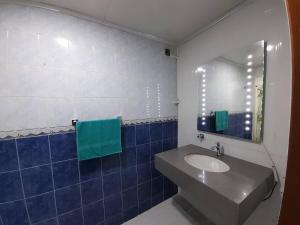 een badkamer met een wastafel, een spiegel en blauwe tegels bij GRAN APARTAESTUDIO EN BOSTON - MEDELLIN in Medellín