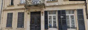 a building with black shuttered windows and a balcony at Le voltaire 1 chez Adrien in Saint-Quentin