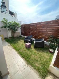 a backyard with two black chairs and a wooden fence at Espacio Planetaria in Córdoba