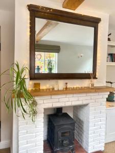a fireplace with a mirror and a black stove at The Town House in Aylsham