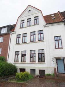 een wit huis met zwarte ramen bij 98qm Wohnung im Villenviertel - Voll ausgestattet mit Balkon und Kamin - WLAN gratis in Wilhelmshaven